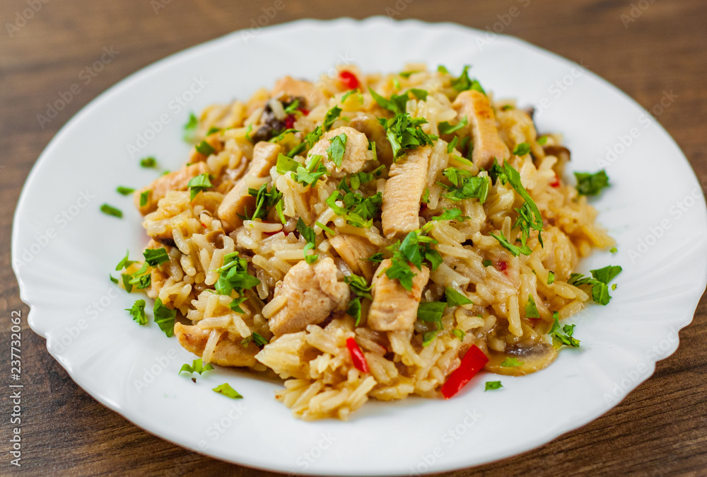 Chicken Breast with Rice, mushroom and vegetables in white plate on wooden table background Chicken Breast with Rice, mushroom and vegetables in white plate on wooden table background
