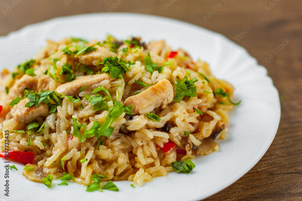 Chicken Breast with Rice, mushroom and vegetables in white plate on wooden table background Chicken Breast with Rice, mushroom and vegetables in white plate on wooden table background