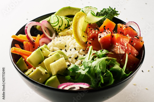 Obraz na płótnie poke bowl with salmon, avocado, cucumber, arugula, broccoli, rice, carrot and sweet onions isolated over white background. side view w salonie
