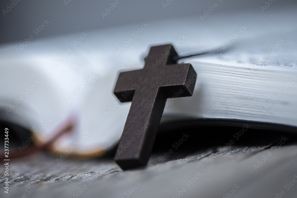 Cross on Bible on wooden table