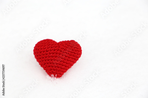 Valentine's day background, red knitted heart in the snow. Symbol of romantic love, concept of blood donation, Christmas mood