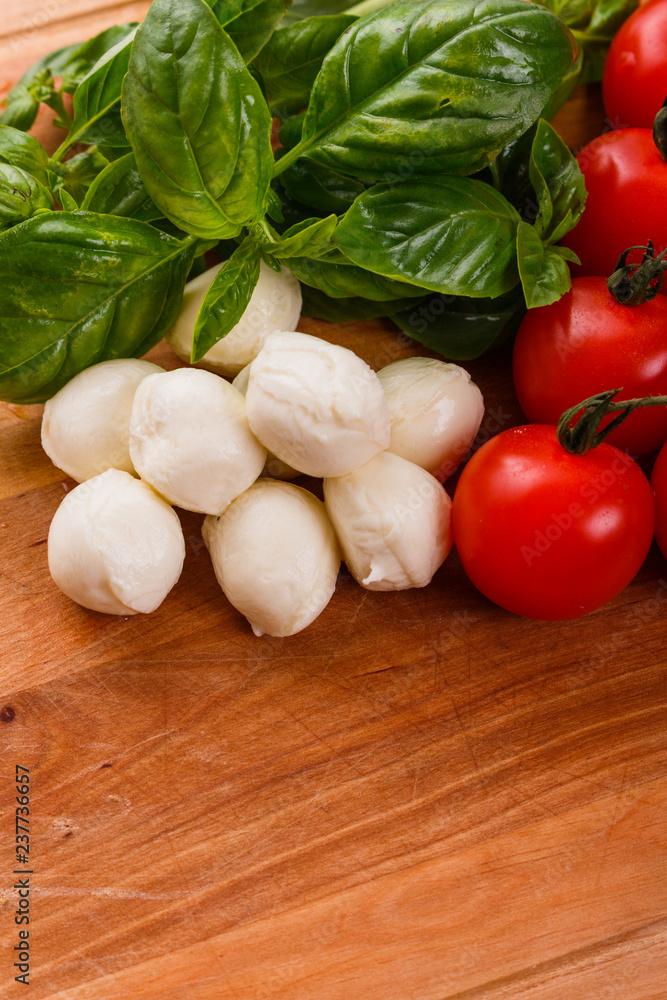 Mozzarella tomatoes and basil on a wooden rustic background Mozzarella tomatoes and basil on a wooden rustic background