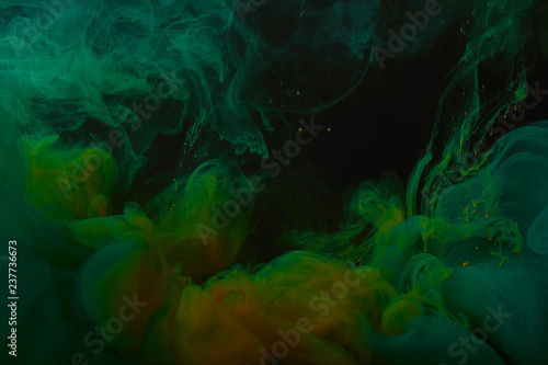close up view of abstract background with green and orange swirls of paint