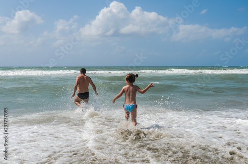 Young dad and daughter swim and play in the sea during the summer holidays