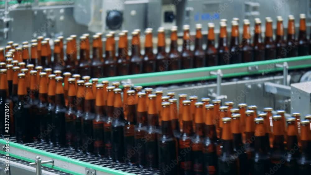 Filled bottles on a brewery conveyor, close up. Filled bottles on a brewery conveyor, close up.