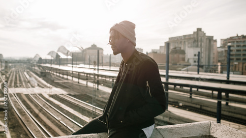 Side view of young african man sitting station train background