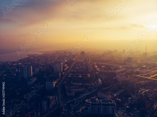 Aerial panorama of dramatic sunset over big city in evening twilight fog or haze, drone view cityscape