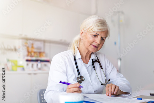 Senior female doctor writing a prescription in her office