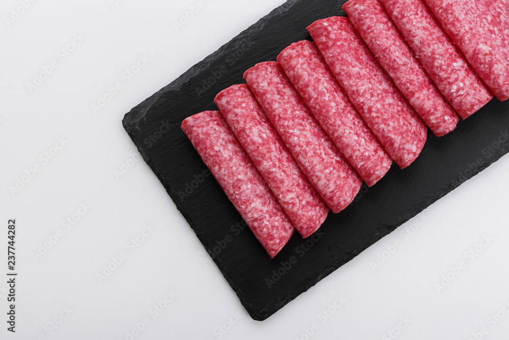 delicious sliced salami on a stone plate white background delicious sliced salami on a stone plate white background