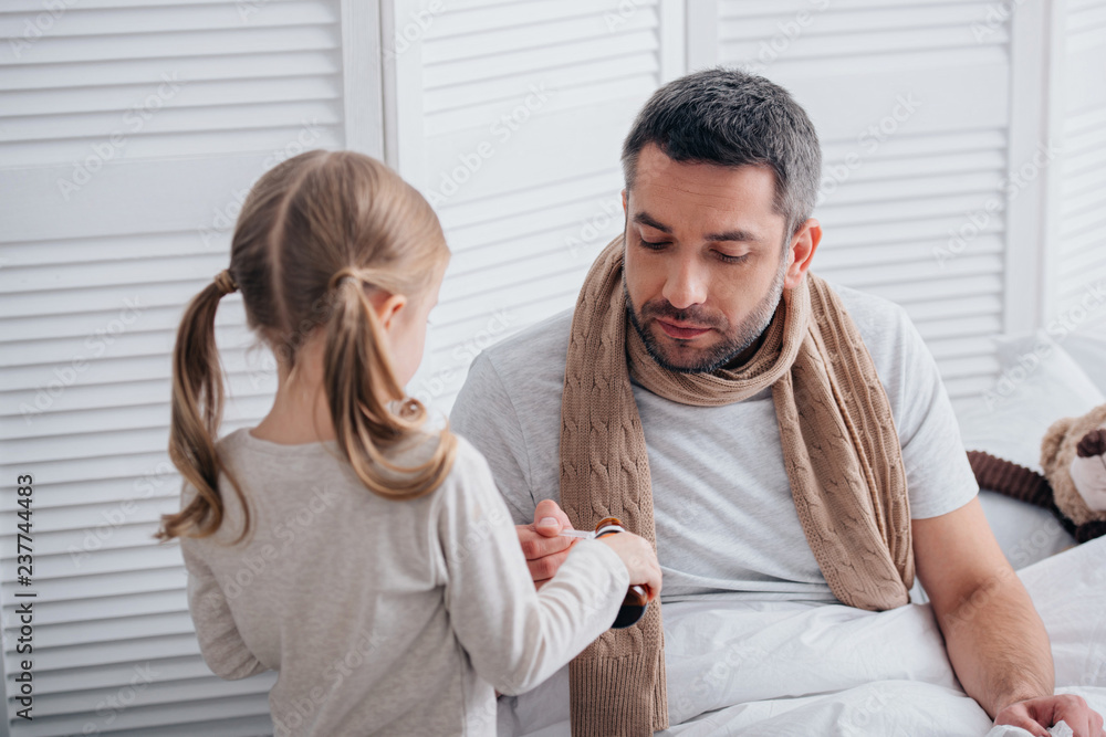 daughter pouring medicines in spoon for sick dad in bedroom daughter pouring medicines in spoon for sick dad in bedroom