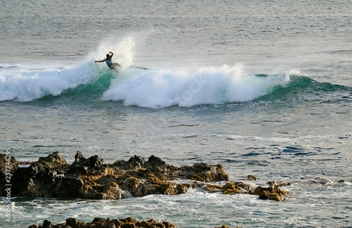 Local young surfer riding on the breaking waves in Pacific Ocean at Hanga Roa, Easter Island, Chile