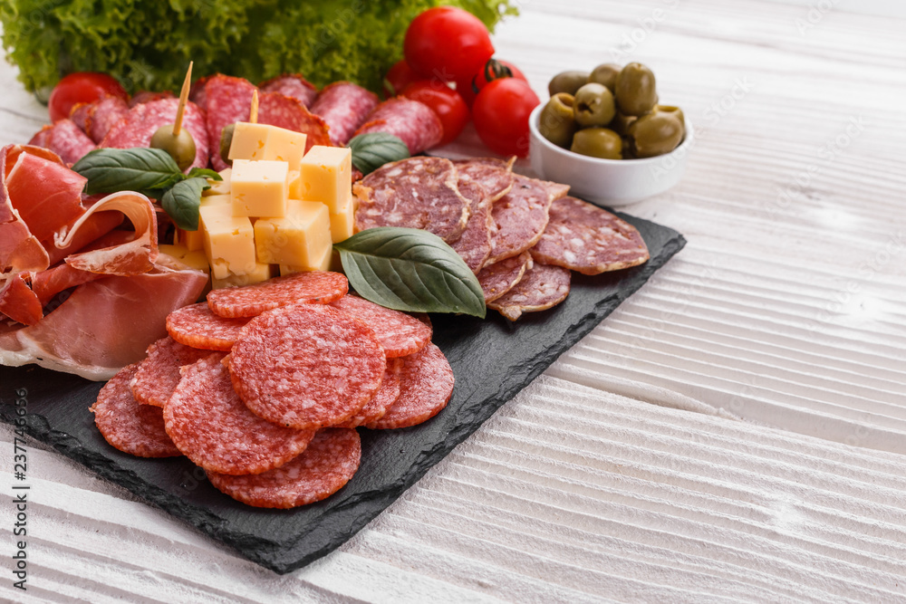 Cold smoked meat plate on a rustic wooden background