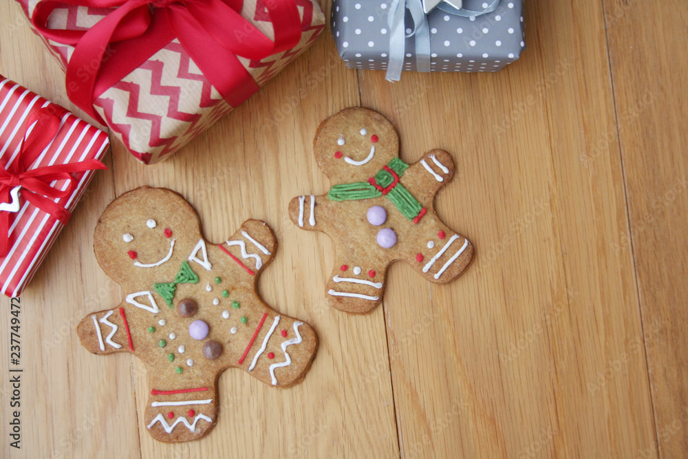 Gingerbread men cookies with gift boxes on wooden table. Christmas background