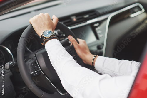 A businessman rides his car, moves on the wheel. A watch on hand in a man's divorce. © standret