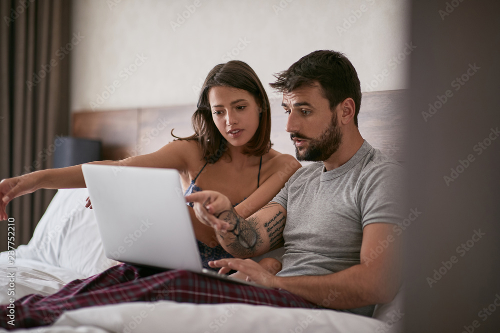 couple discussion in the bed with laptop and surfing on internet. Modern lifestyle concept..