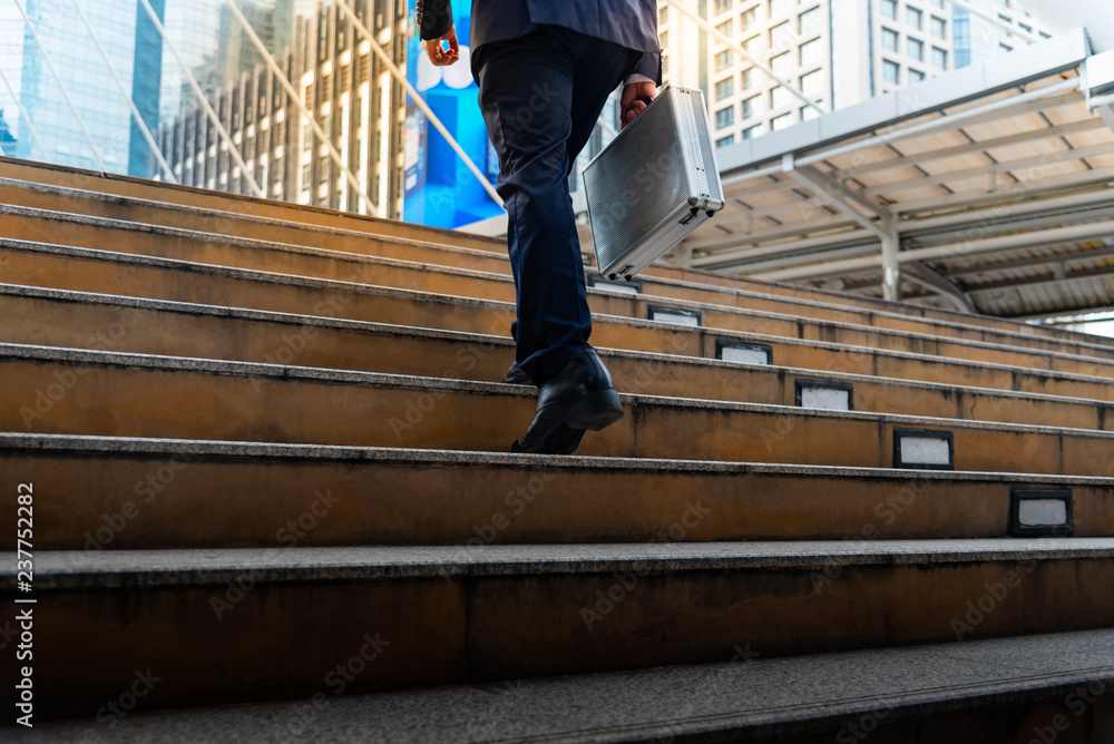 Businessman carrying a briefcase walk up stair To discuss business At the office building with a tall in the downtown, to successful concept.