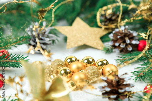 New Year's background. Christmas jewelry on fir-tree branches, gold spheres, garlands, a big gold star of an ishishka on branches. White background