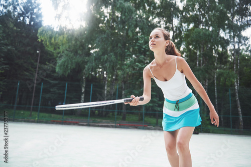 Woman in sportswear serves tennis ball.