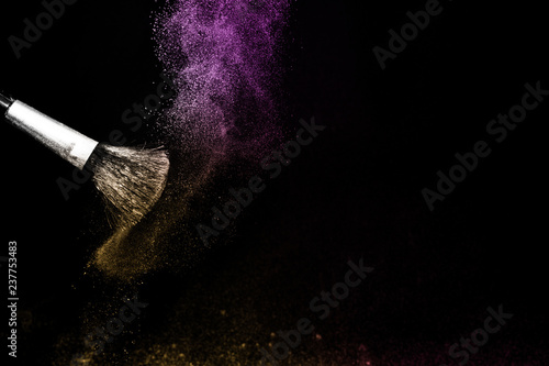 gold and purple powder splash and brush for makeup artist or beauty blogger in black background