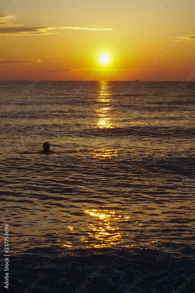 Swimming woman enjoying the sunrise of Aegean sea.