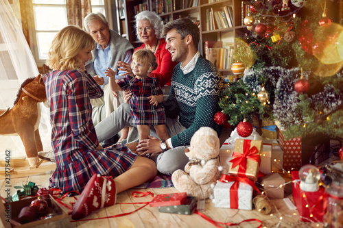 Foto Christmas family portrait - family sitting on floor front of beautiful Christmas tree