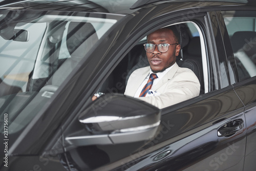 front view of Handsome african elegant serious business man drives a car