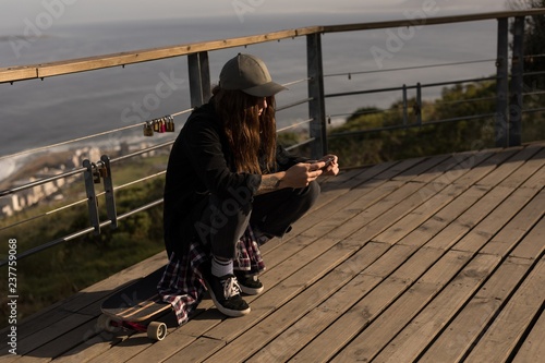 Wallpaper Mural Female skateboarder using mobile phone at observation point Torontodigital.ca