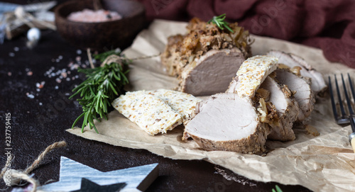 Roast pork meat with onion, garlic and rosemary served with nuts butter on brown stone table. 