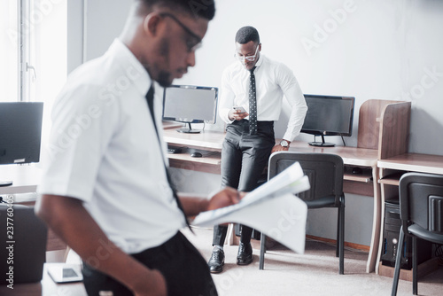 Discussing a project. Two black business people in formalwear discussing something while one of them pointing a paper