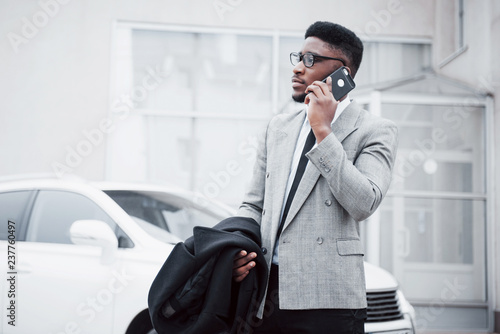 Portrait of a confident young businessman walking in the city talking on cell phone