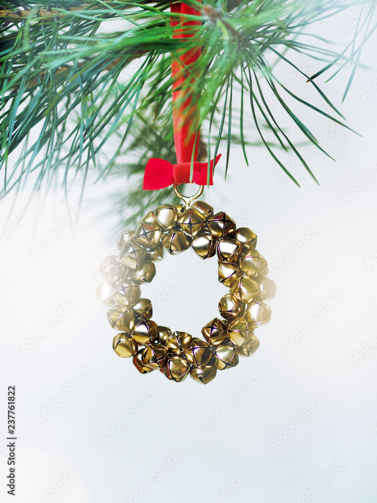 Christmas card with a wreath of bells on a fir branch with the effect of snow and bokeh on light background Christmas card with a wreath of bells on a fir branch with the effect of snow and bokeh on light background