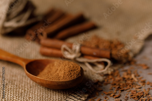 Placer crushed cinnamon and cinnamon sticks on a textured background with textiles under the burlap.