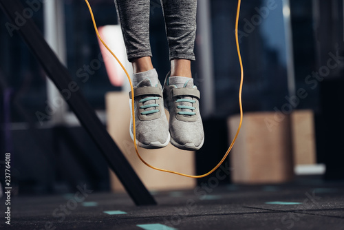 cropped view of female legs jumping with skipping rope at gym photo