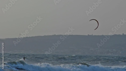 A Kitesurfer alone surfing in a rough sea in a cloudy day at Santa Sevara, near Rome, Italy.
