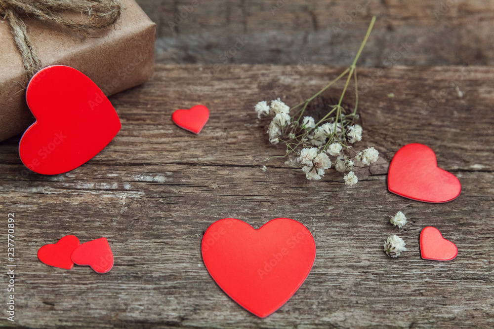 Fototapeta premium Gift box present wrapped craft paper with red hearts on rustic trendy old vintage wooden background. Christmas happy Holiday greeting card anniversary Christmas, new year, valentine day, birthday