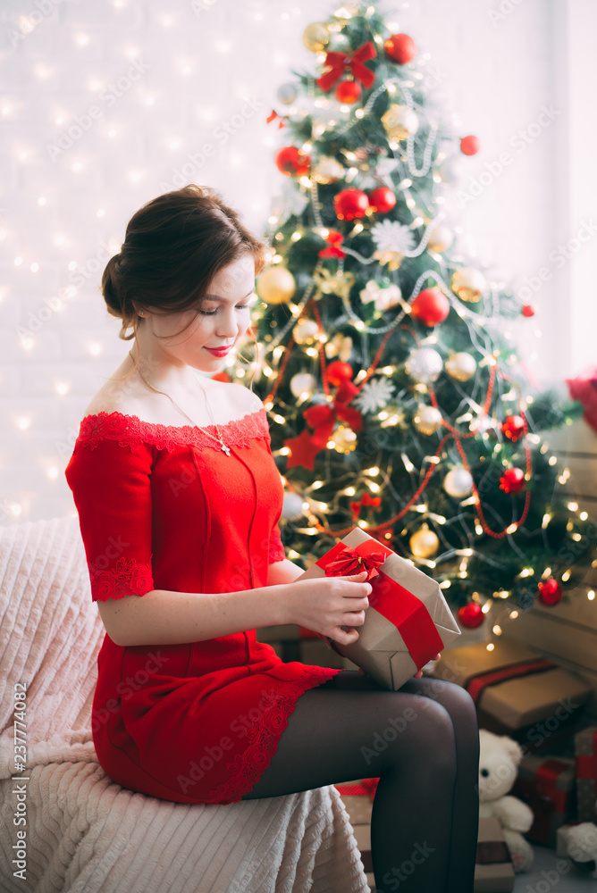 New year girl with a gift in her hands near the Christmas tree New year girl with a gift in her hands near the Christmas tree