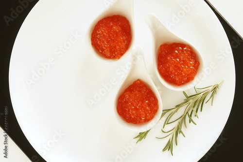 red caviar in small bowls on white background. top view.copy space