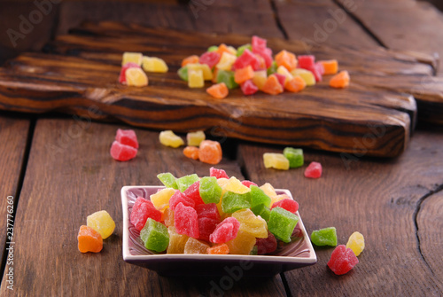 Multicolored dry fruits in a bowl on a wooden table.
