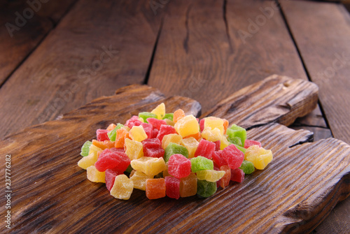 Multicolored dry fruits in a bowl on a wooden table.
