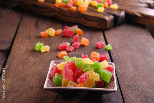 Multicolored dry fruits in a bowl on a wooden table.
