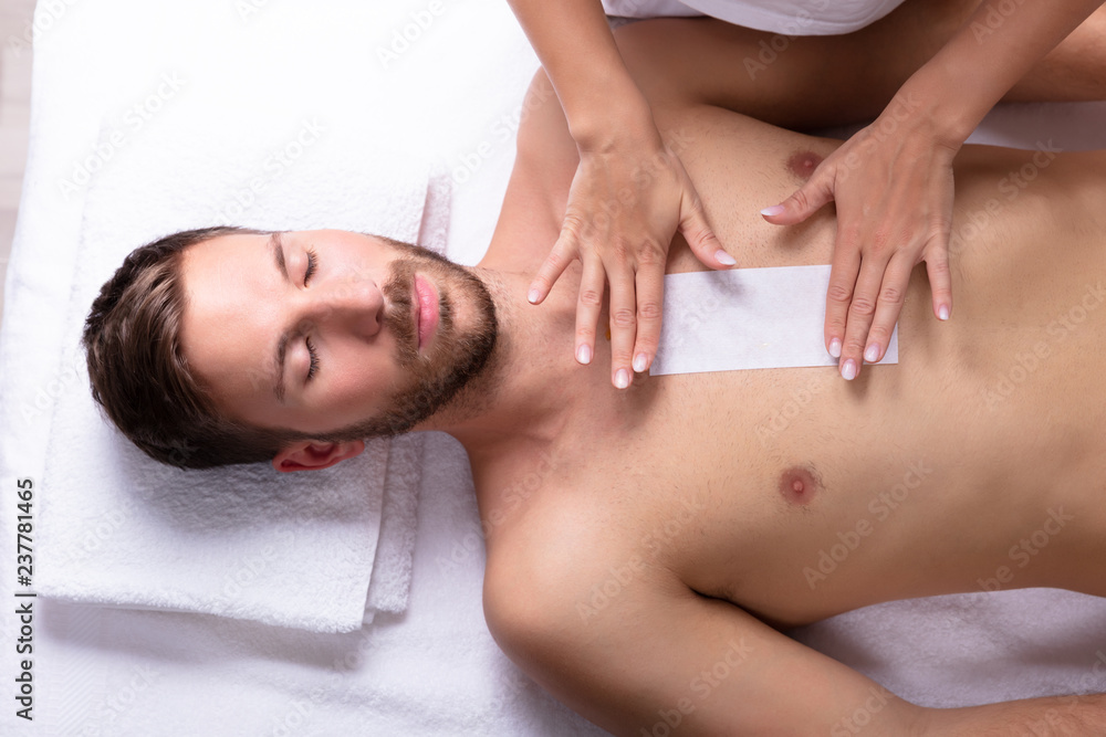 Beautician Waxing Man's Chest With Wax Strip