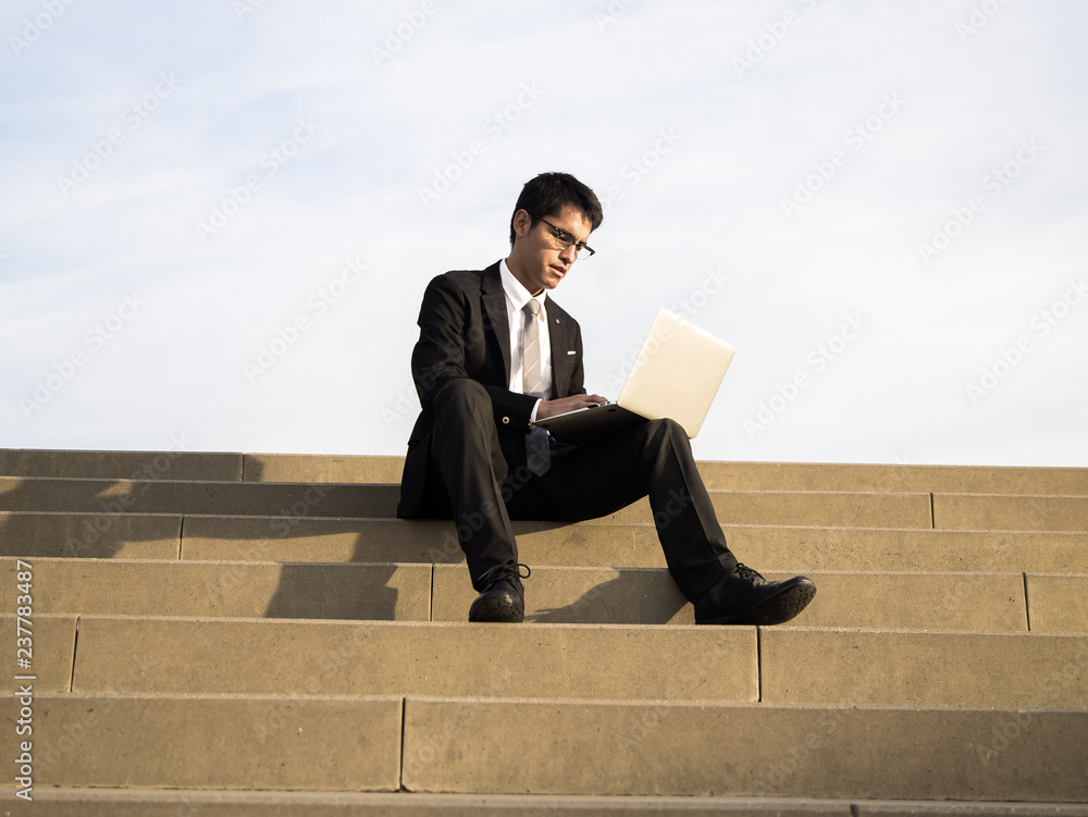 man wearing a suit working with his laptop outdoor man wearing a suit working with his laptop outdoor