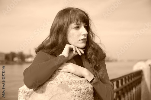 The thoughtful young girl on quay. portrait in a retro style photo