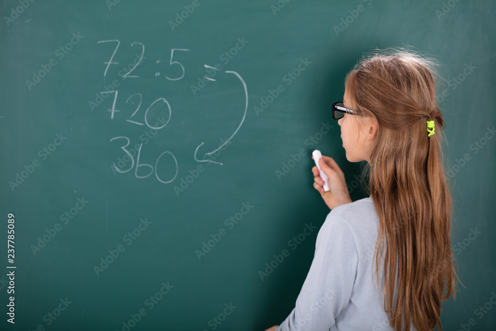 Girl Solving Mathematics On Chalkboard