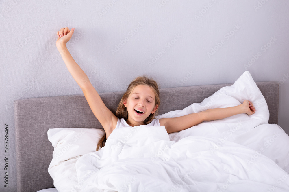 Girl Sitting On Bed Stretching Her Arms Girl Sitting On Bed Stretching Her Arms