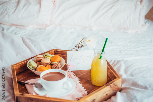 Breakfast in bed with i love you text on a note. Cup of coffee or cocoa, juice, macaroons, rose flower on wooden tray. Romantic breakfast in bed. Birthday, Valentine's day morning. Copy space.