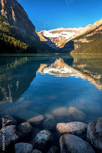 Wall Mural Water reflection with rocks in the foreground and snowcape in the background in