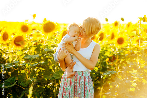 Photo of mother hugging her little boy in sunflower surroundings photo