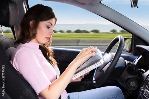 Woman Reading Book While Driving Car photo