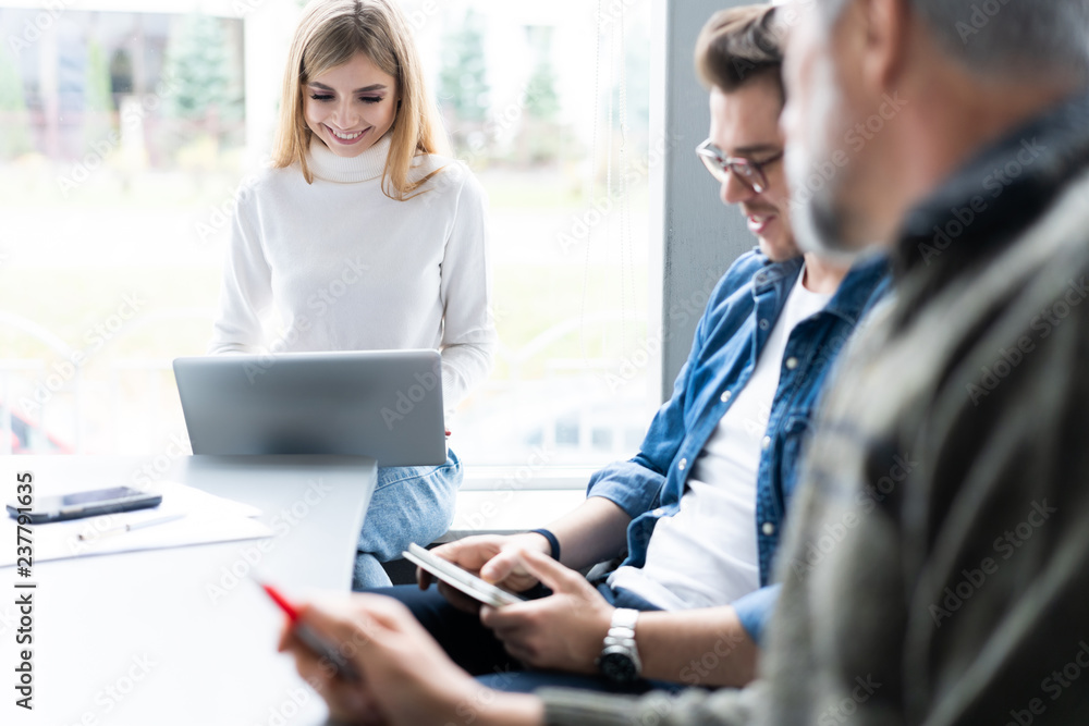 Working day. Group of young modern people in smart casual wear discussing business while working in the creative office. Working day. Group of young modern people in smart casual wear discussing business while working in the creative office.